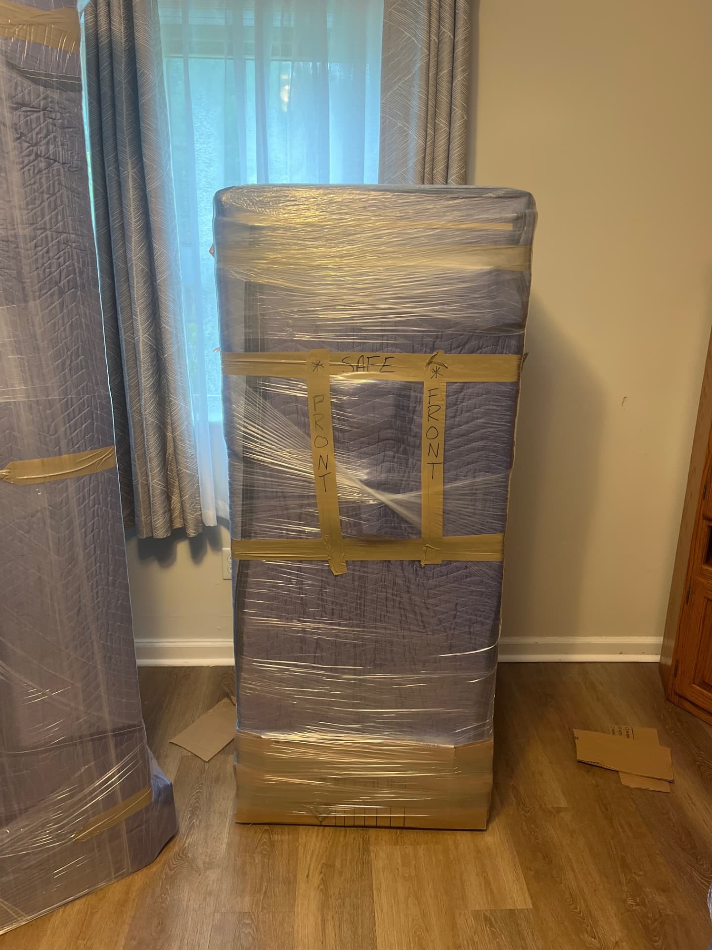 A couch professionally wrapped in plastic and tape, marked for safe handling